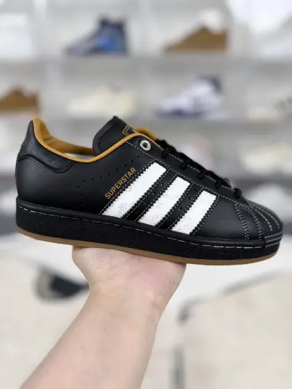 ▪️D版纯原 adidas originals Superstar 2 牛剖层革 舒适经典 低帮 板鞋 男女同款 黑棕 ▪️ (352⁄3 36 362⁄3 371⁄3 38 382⁄3 391⁄3 40 402⁄3 411⁄3 42 422⁄3 431⁄3 44 451⁄3) ▪️货号:KI6590 ▪️Superstar系列以贝壳头设计著称,这一标志性元素使其在众多鞋款中脱颖而出.贝壳头不仅具有防撞和保护脚尖的作用,还成为了时尚界的经典符号.作为阿迪达斯经典系列的一部分,Superstar鞋侧常常饰有三叶草标志,彰显品牌身份与品质保证.鞋面采用优质皮革,质感高级且耐磨耐穿.柔软橡胶底则提供了良好的缓震效果和抓地力.Superstar板鞋以其舒适的穿着体验而著称.柔软橡胶底和合理的内部空间设计,使得长时间穿着也不会感到疲劳.简约复古的鞋型搭配贝壳头设计,使得Superstar成为一款百搭鞋款.无论是搭配牛仔裤、休闲裤还是裙子,都能轻松驾驭各种风格.采用优质材质和精湛工艺打造,Superstar板鞋具有出色的耐用性和耐磨性,能够陪伴消费者度过漫长的时光.自诞生以来,Superstar逐渐成为街头潮流文化的代表之一.众多潮人、明星和设计师都钟爱这款鞋款,纷纷将其纳入自己的穿搭中.